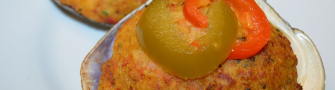 Two savory stuffed scallops, one garnished with a pickle and pepper slice.